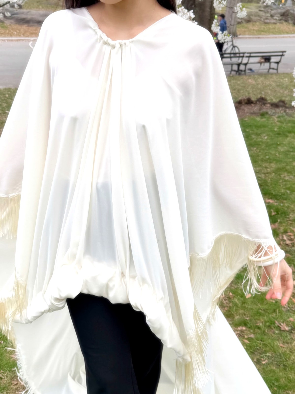 Ivory silk cape with fringed hem photographed outdoors
