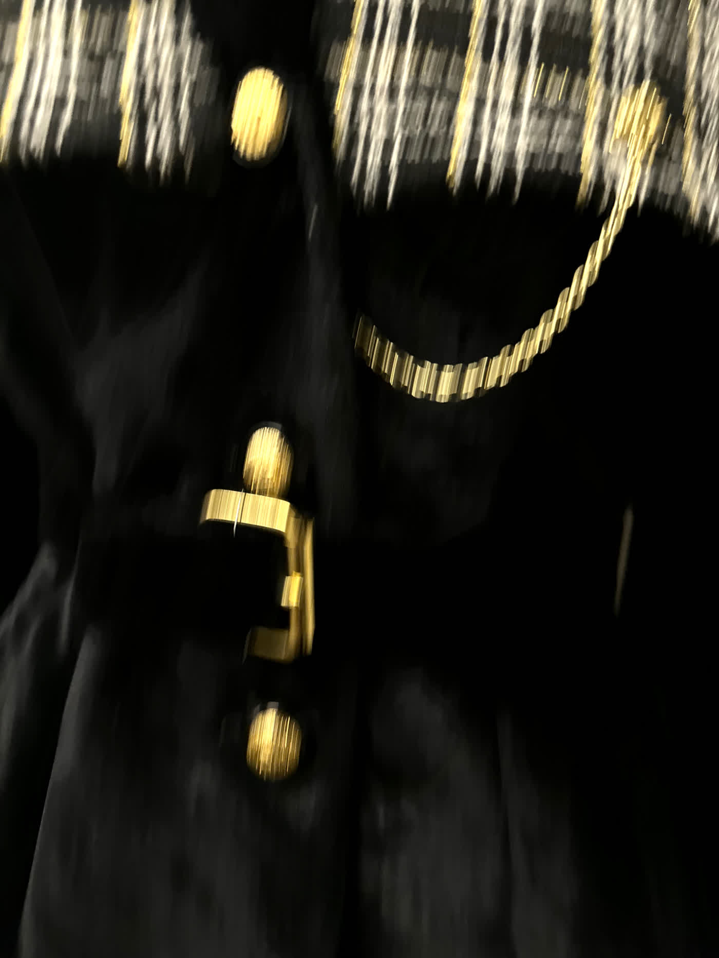 Close-up of the domed brass buttons, gold chain and buckled belt on the black velvet