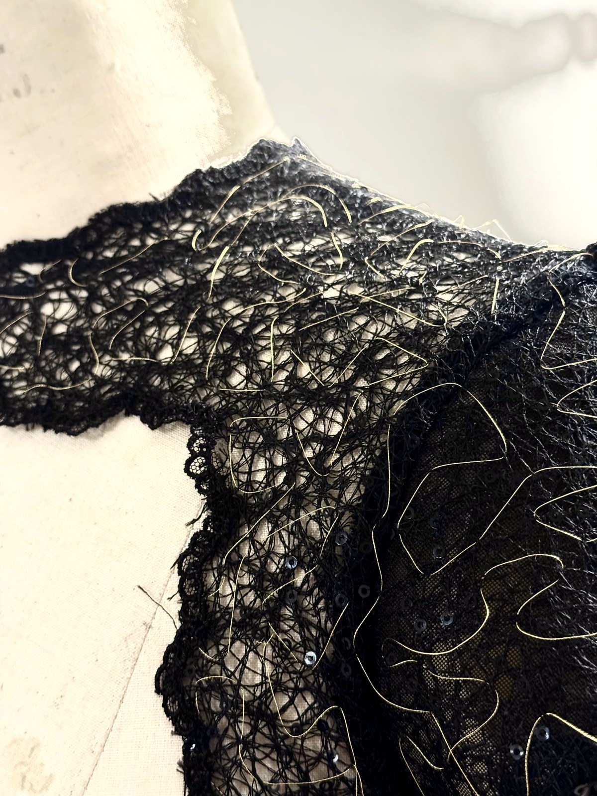 Close detail of black lace embroidered with gold thread and sequins on a shoulder